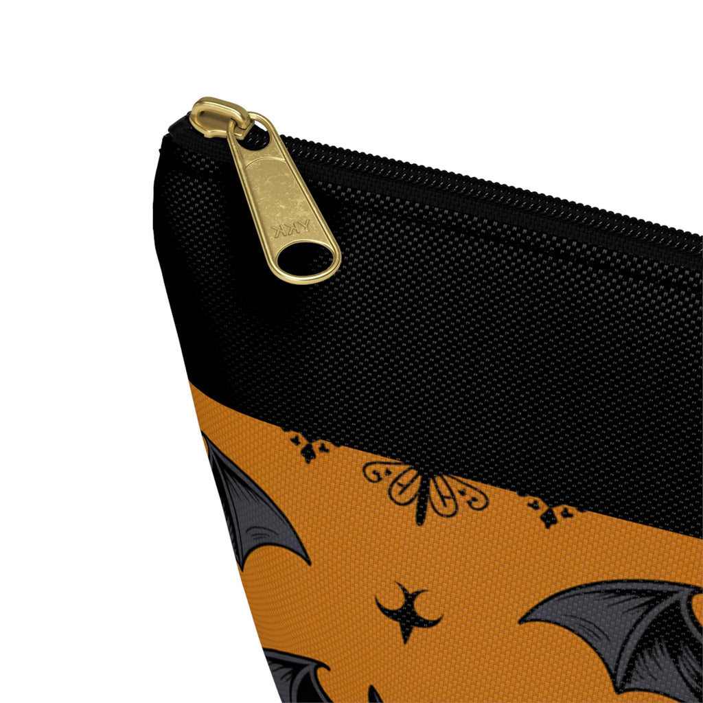 Close-up of gold zipper pull on black top of bat print pouch