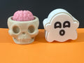 Skull cup with pink brain and white ghost fidget clicker side by side