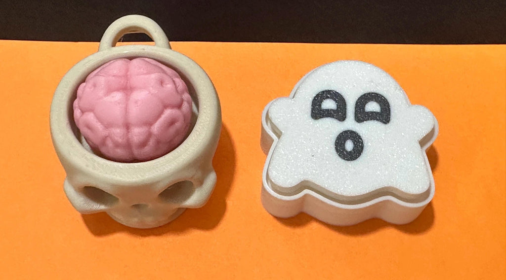 Top-down view of skull brain cup keychain and ghost fidget clicker