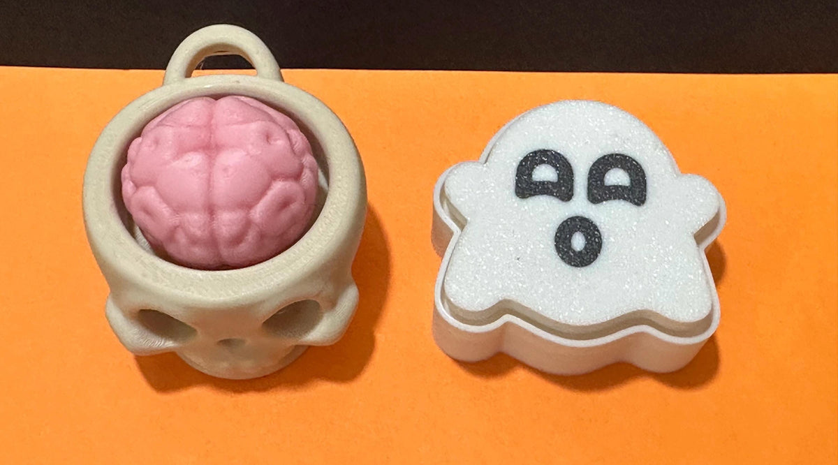 Top-down view of skull brain cup keychain and ghost fidget clicker