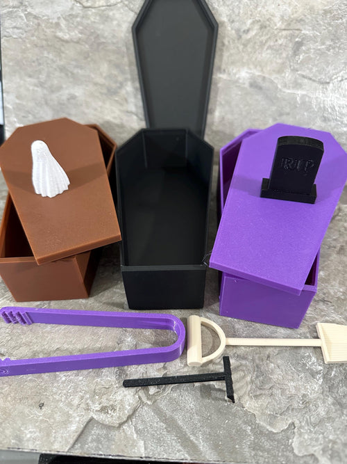 Three coffin boxes in brown, black and purple with lids and zen garden tools