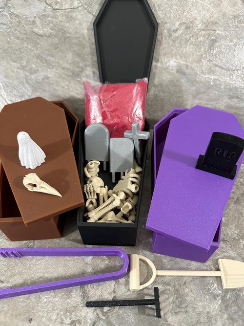 Coffin zen garden kit with skeleton parts, tombstones, red sand and garden tools