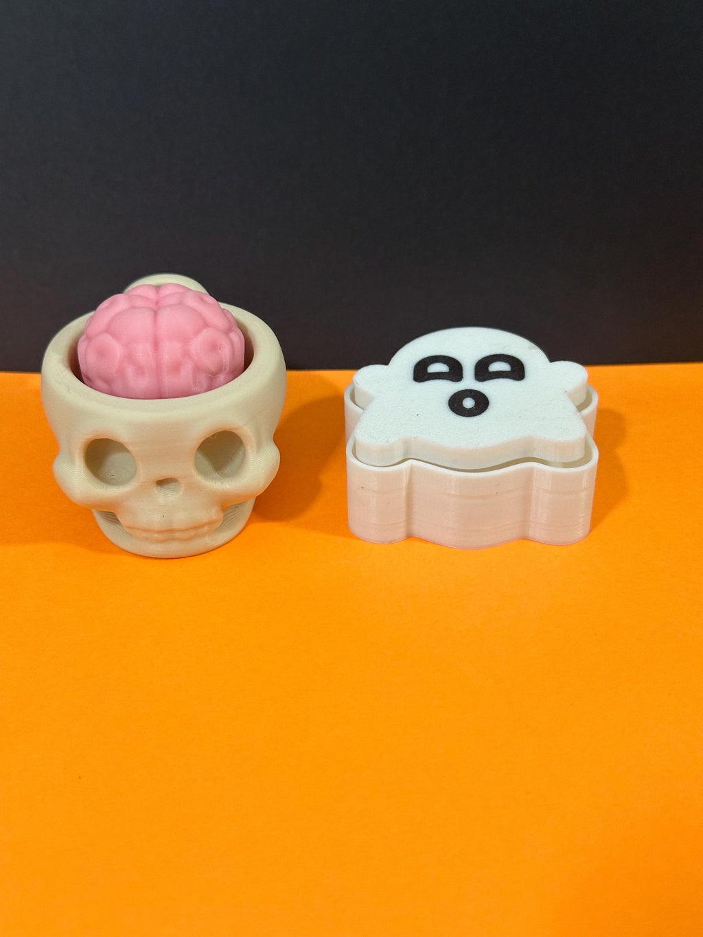 Skull cup with pink brain and ghost clicker fidget toys on orange background