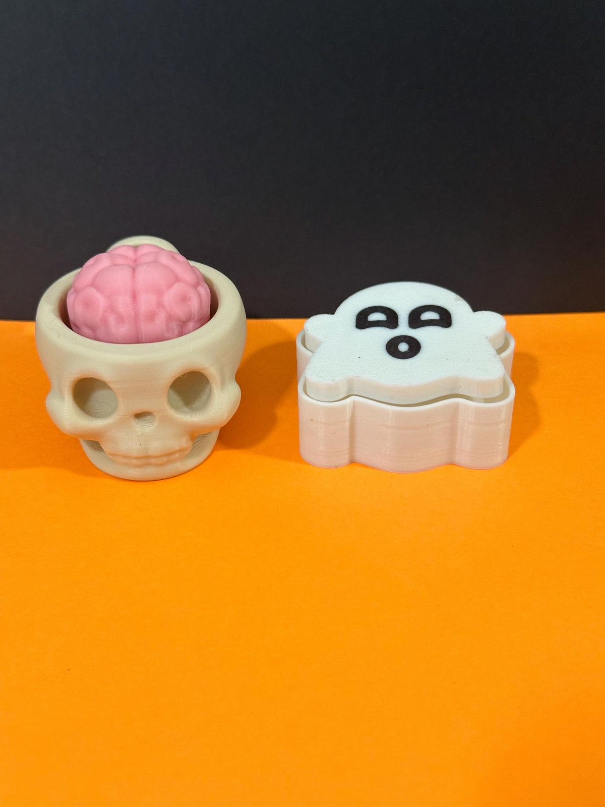 Skull cup with pink brain and ghost clicker fidget toys on orange background