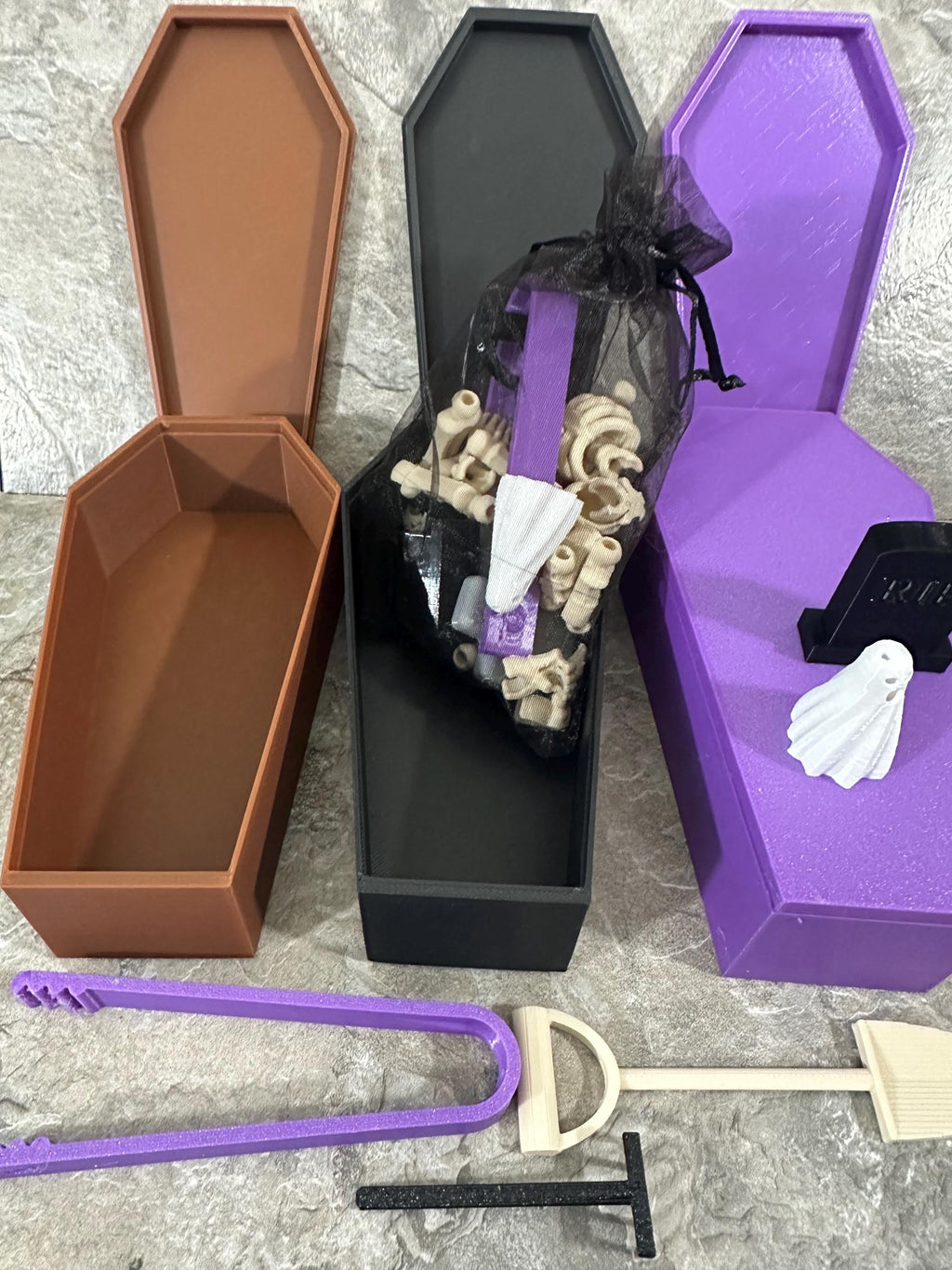 Overhead view of three open coffin boxes with skeleton parts and garden tools