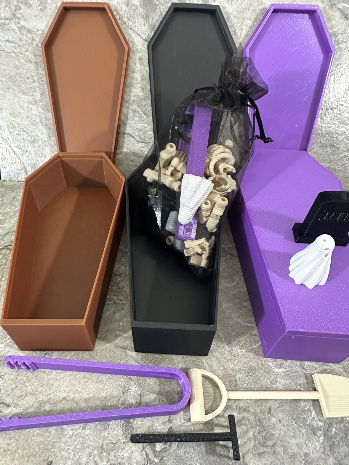 Overhead view of three open coffin boxes with skeleton parts and garden tools