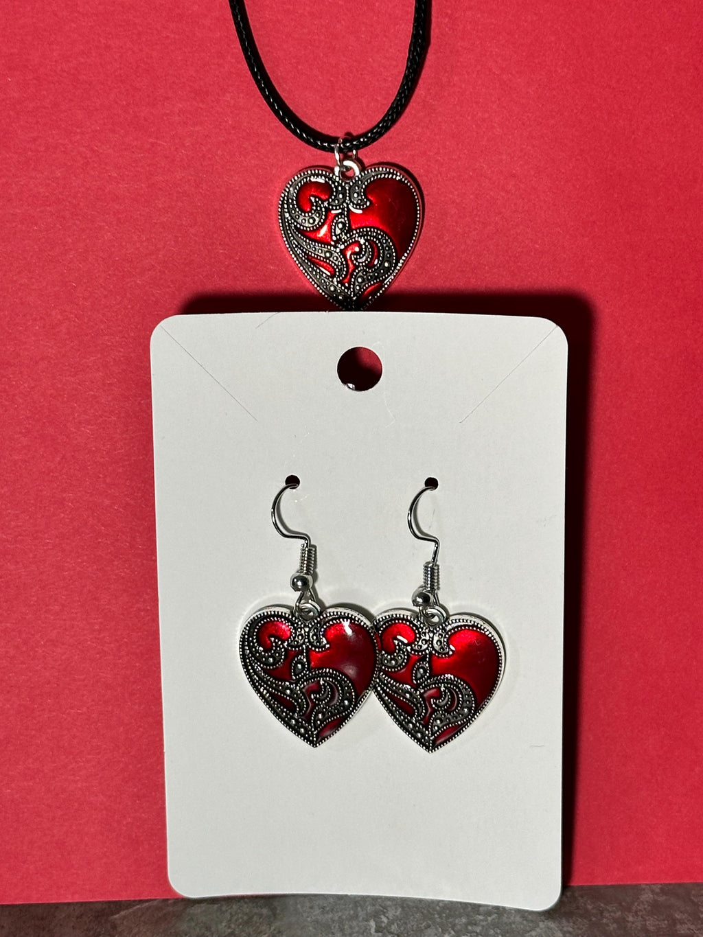 Red enamel heart jewelry set: pendant necklace above dangle earrings on card