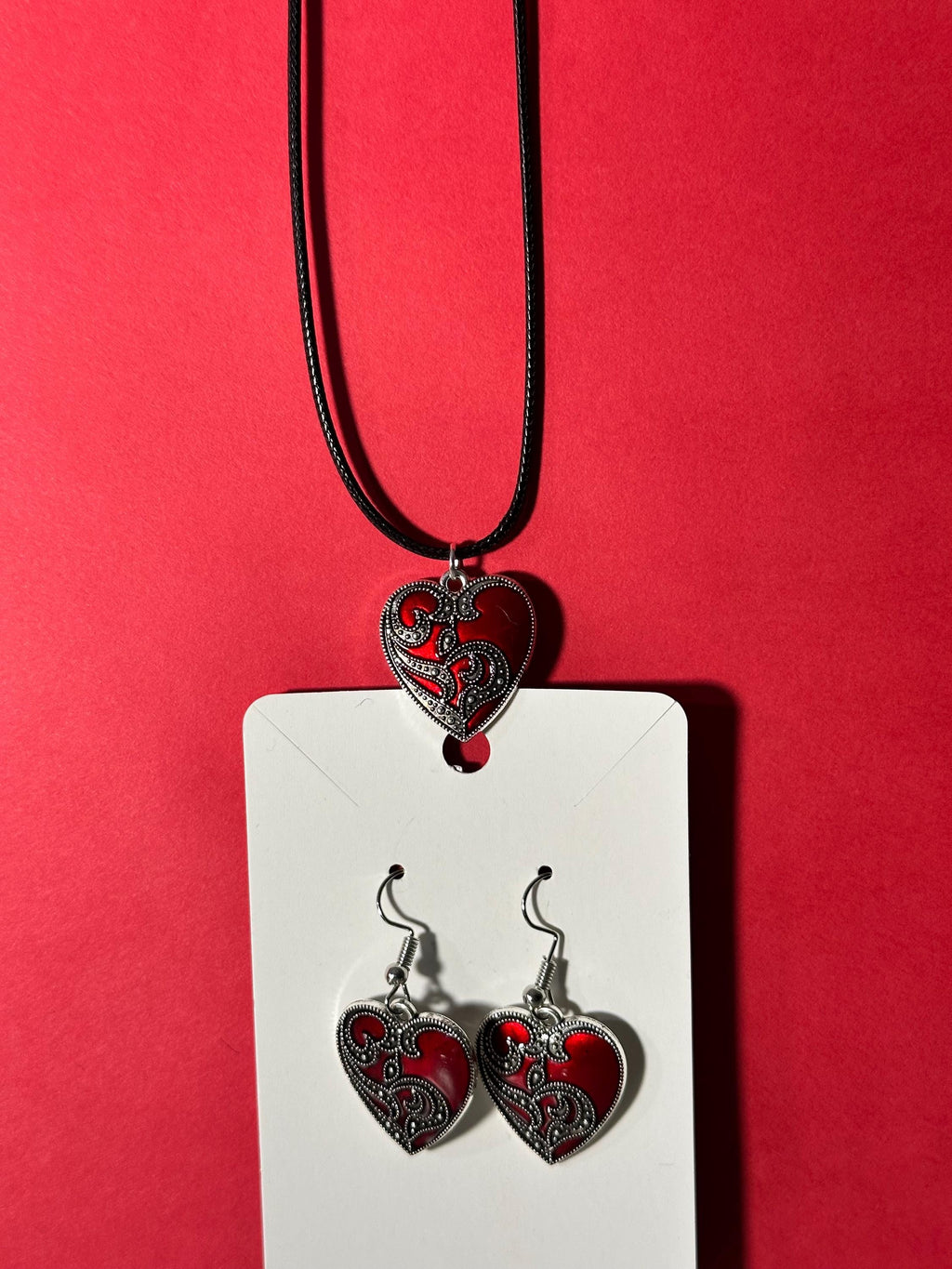 Matching red heart pendant and earring set displayed on white card