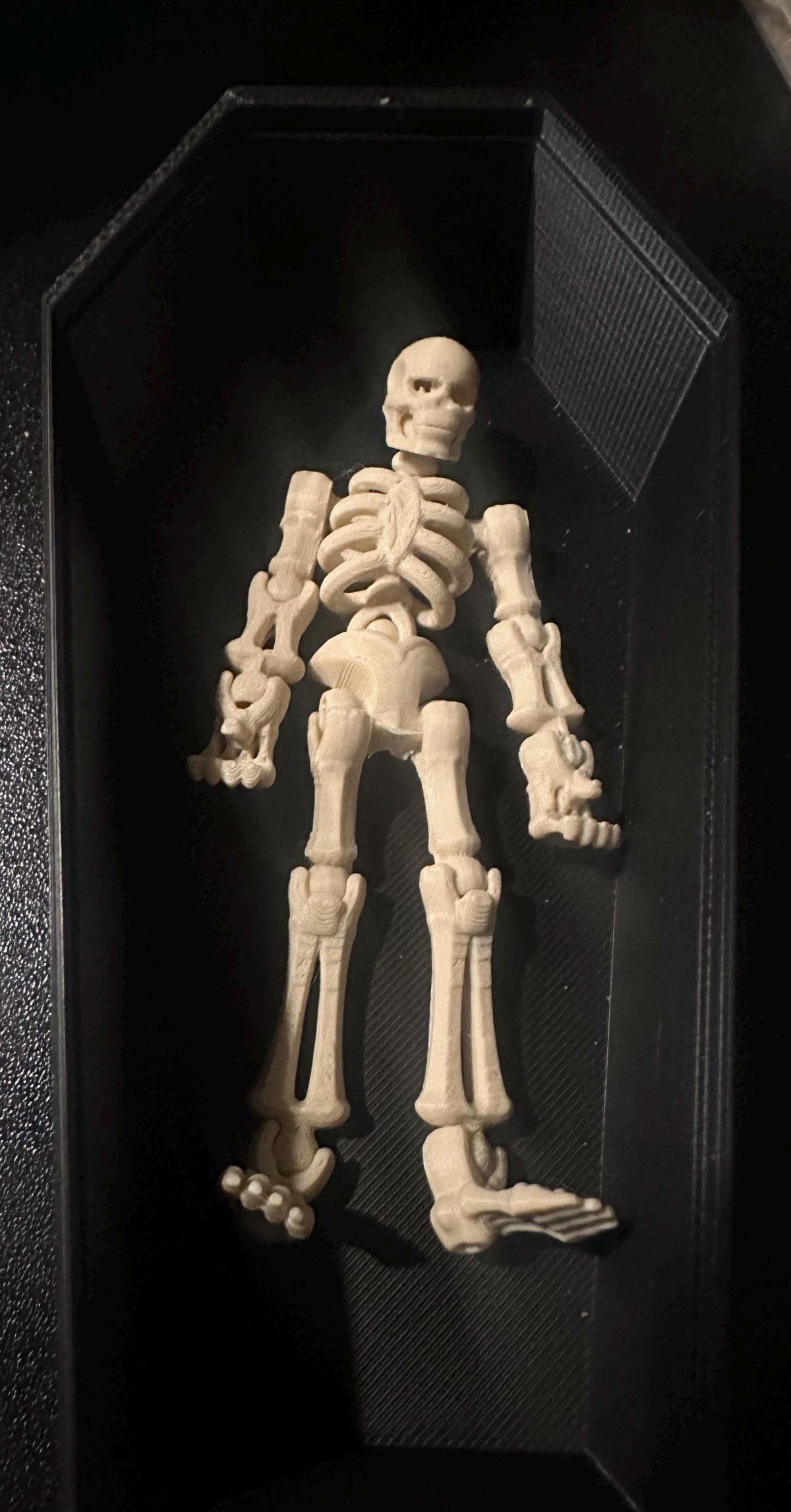 Two beige skeleton buddy figures side by side on black surface