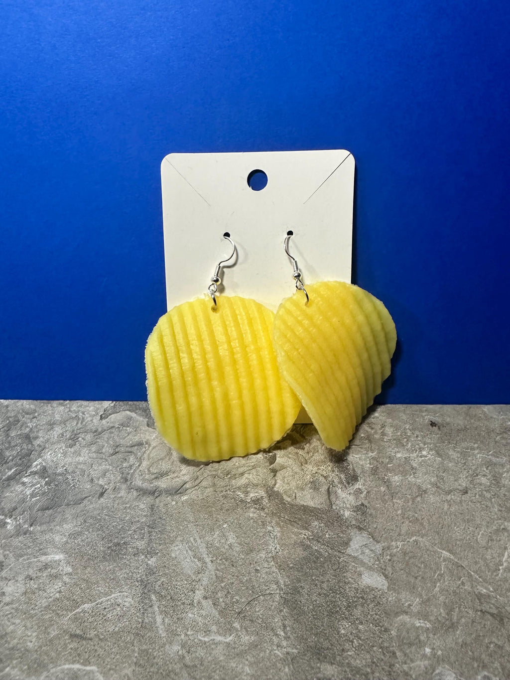 Ridged potato chip earrings on white display card against blue background