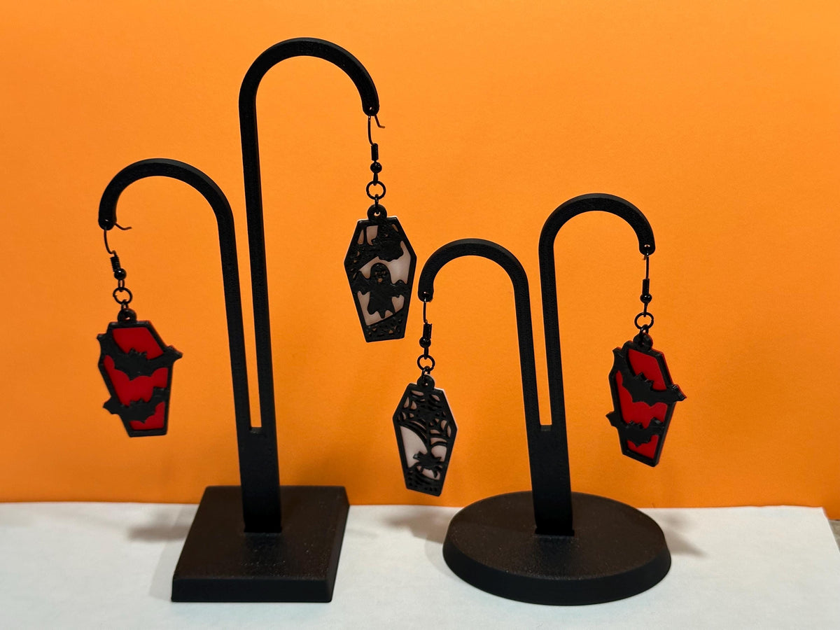 Red bat and black ghost coffin dangle earrings hanging on black earring stands