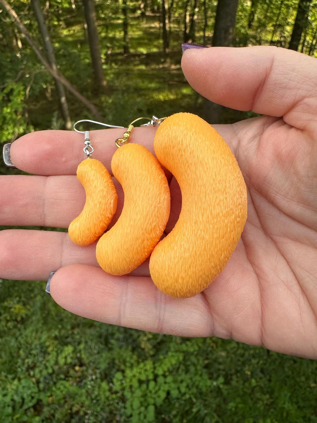 Three 3D printed cheese puff earrings in small, medium and large with silver and gold hooks in hand