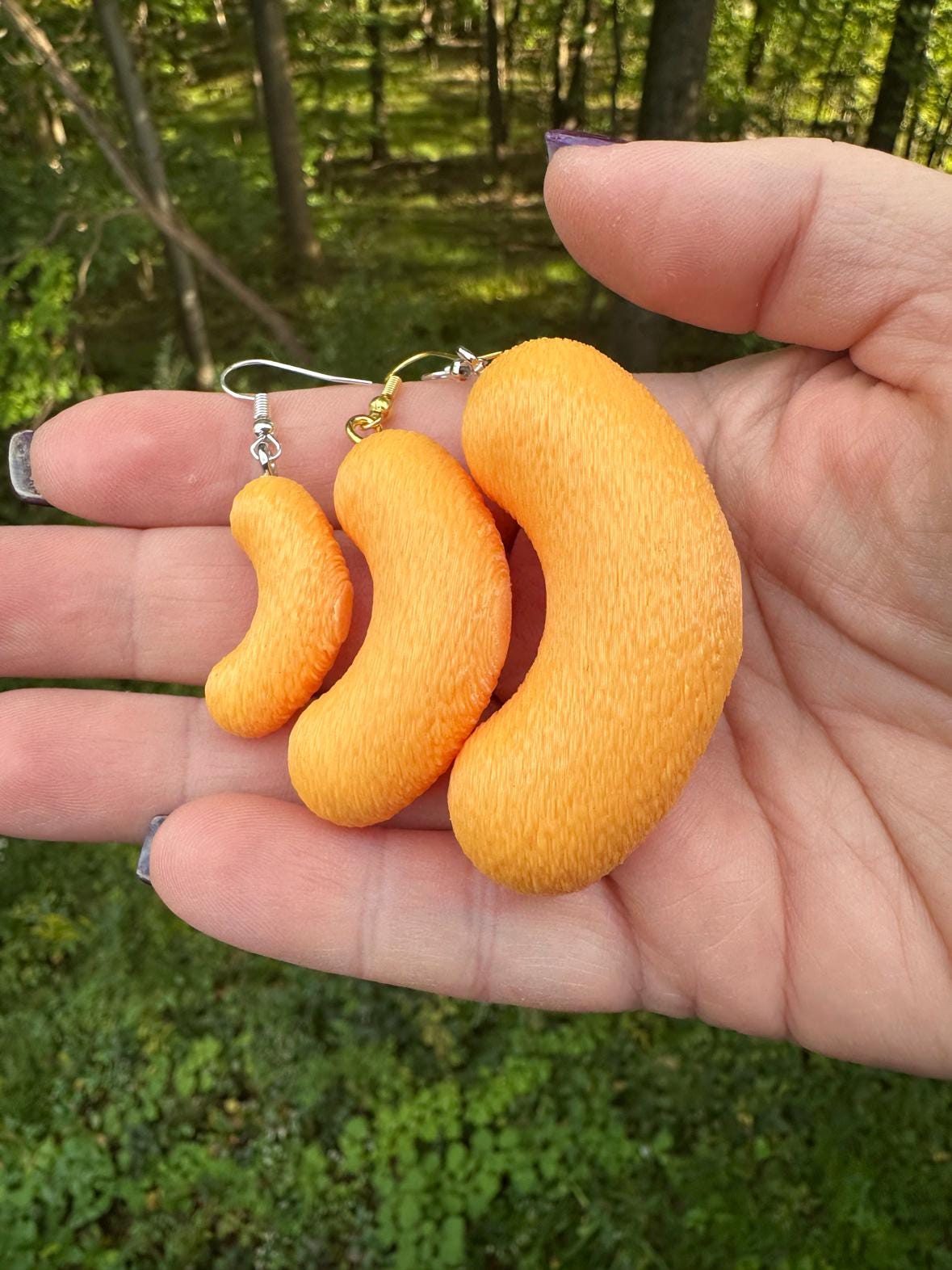Three 3D printed cheese puff earrings in small, medium and large with silver and gold hooks in hand